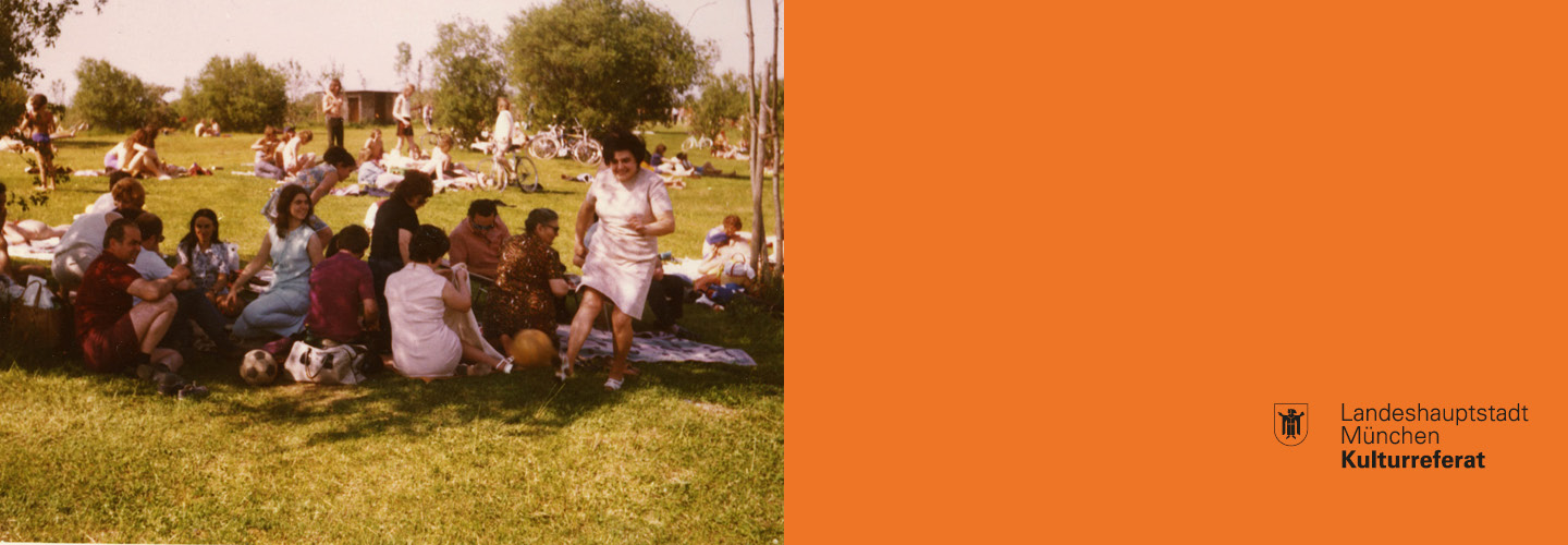 Slider image "City is Migration". The picture shows a colour photograph of a group of people sitting on picnic blankets in a park. A woman from the group, wearing a pink summer dress, has stood up and is laughing at the camera.